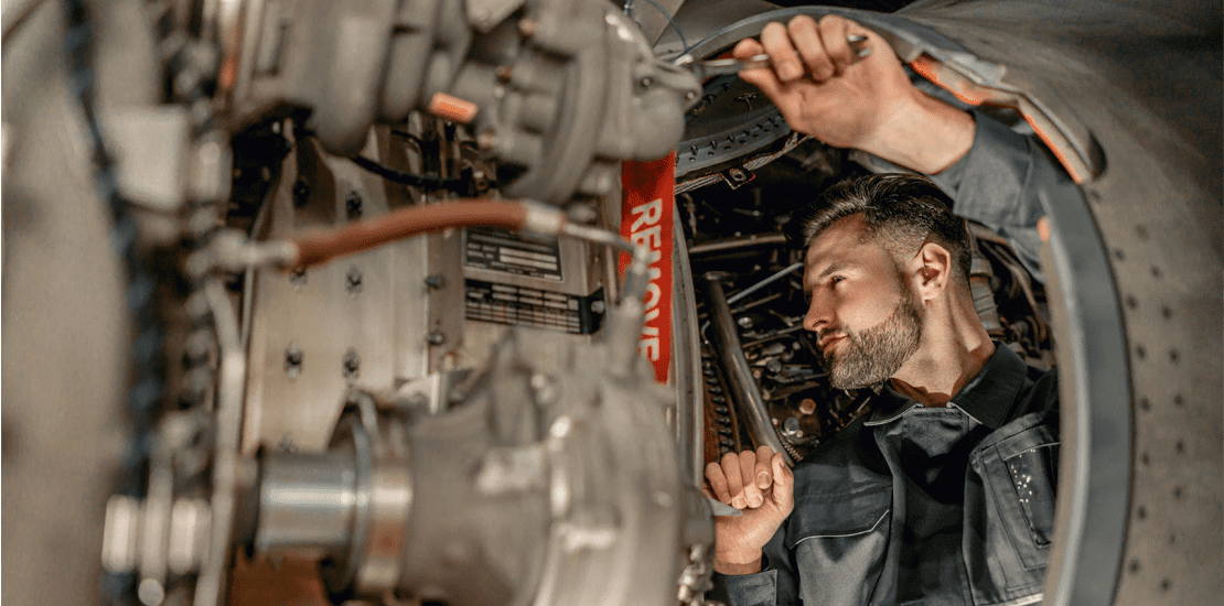 bearded man mechanic repairing aircraft in hangar